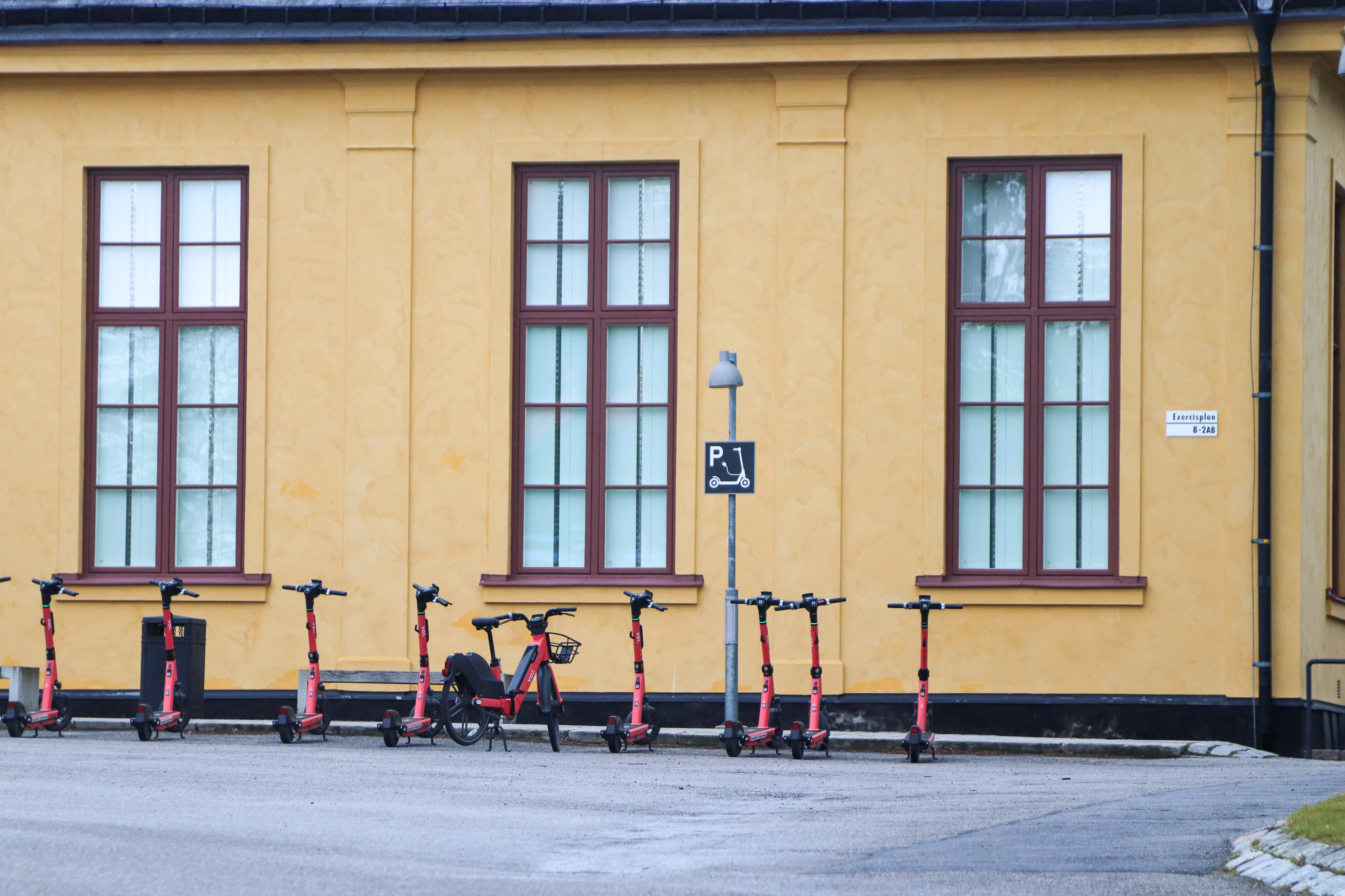 Scooters lined up in front of a yellow building.