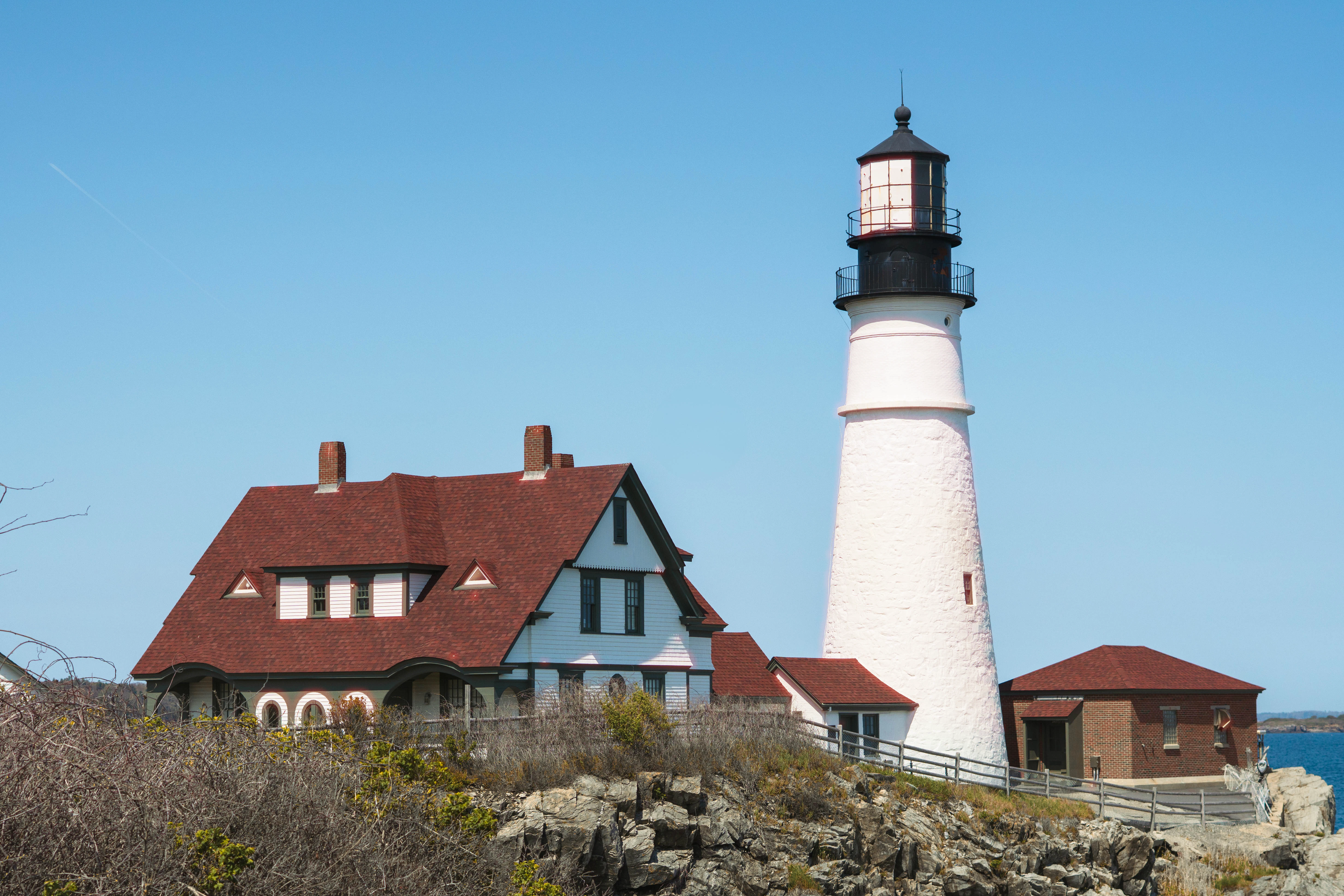 White lighthouse and buildings on rocky coast.