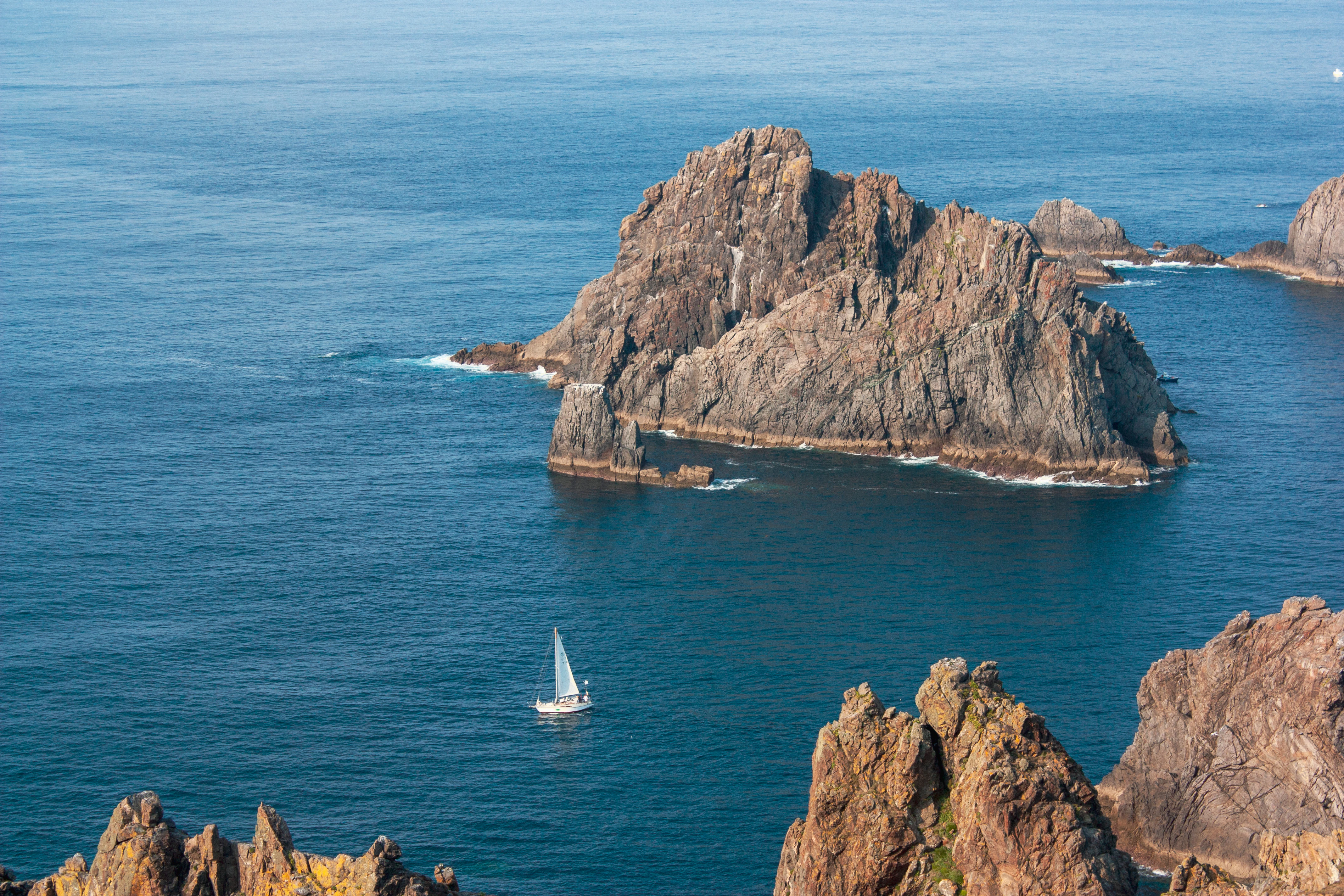a sailboat in the ocean near some rocks