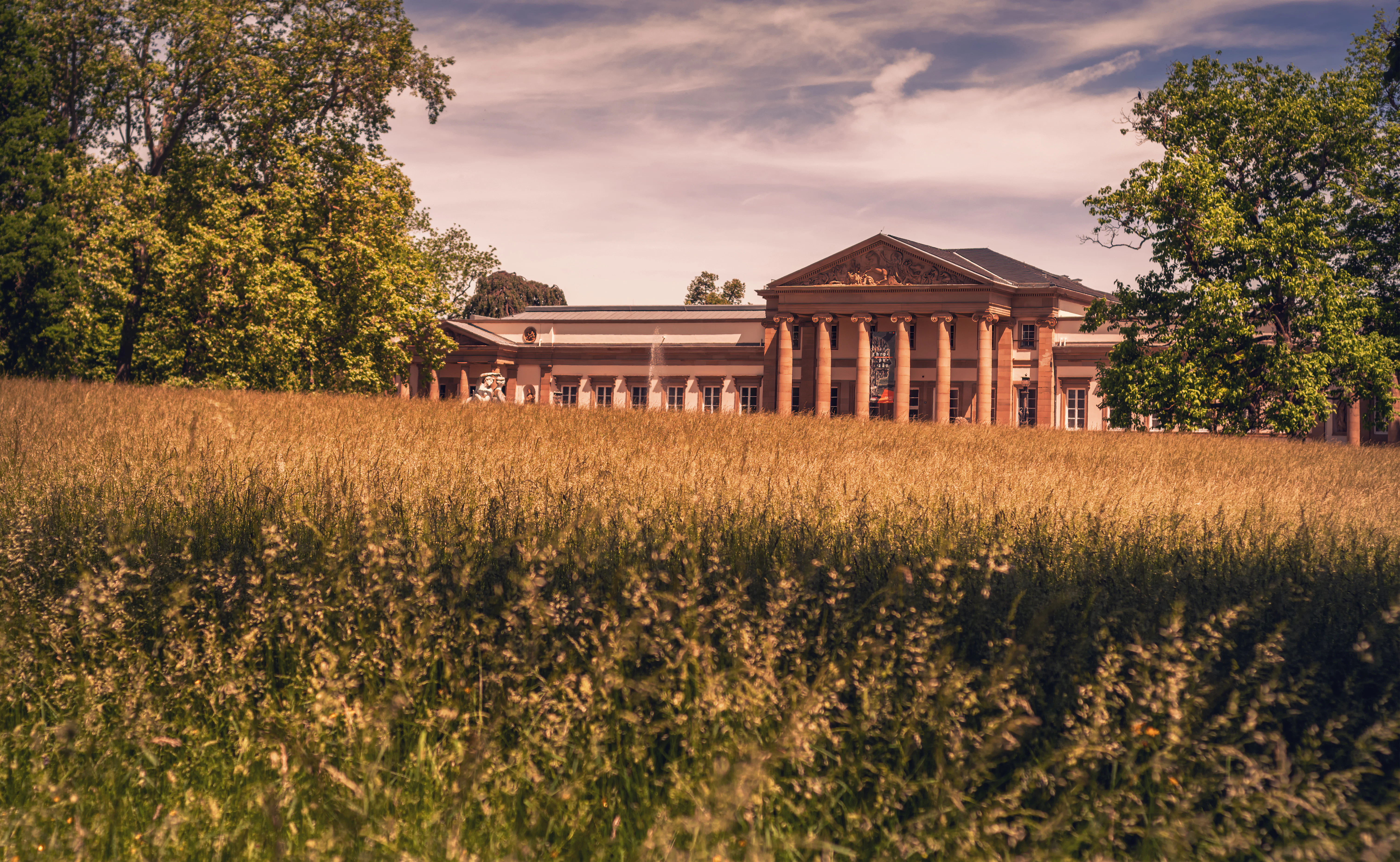 A grand building sits atop a grassy hill.