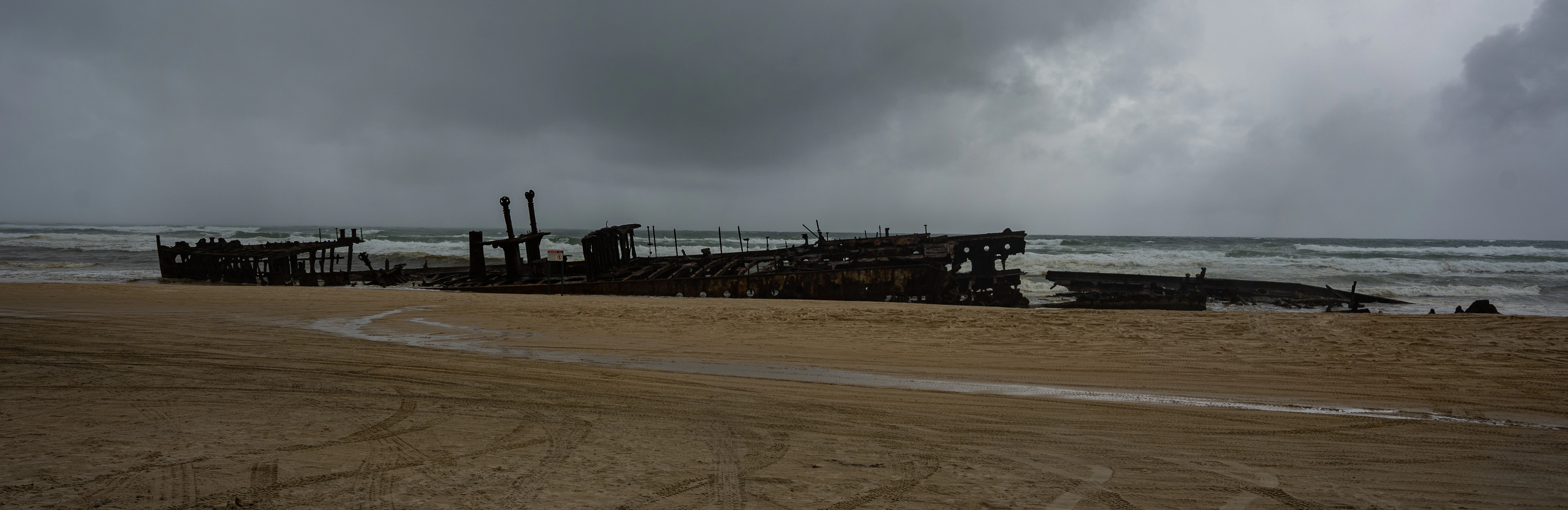 a boat sitting on top of a sandy beach next to the ocean
