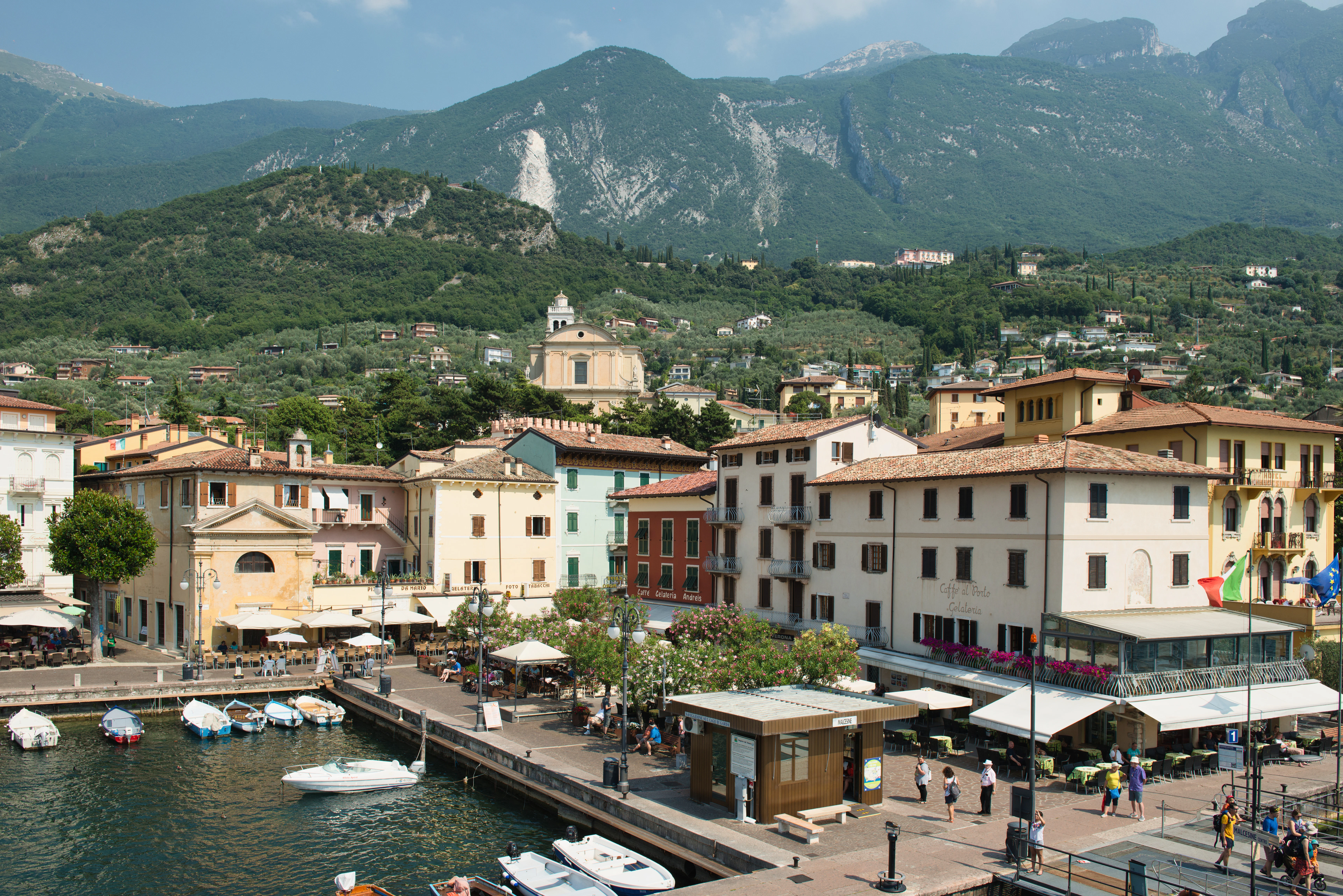 Colorful buildings line a harbor with boats and mountains.