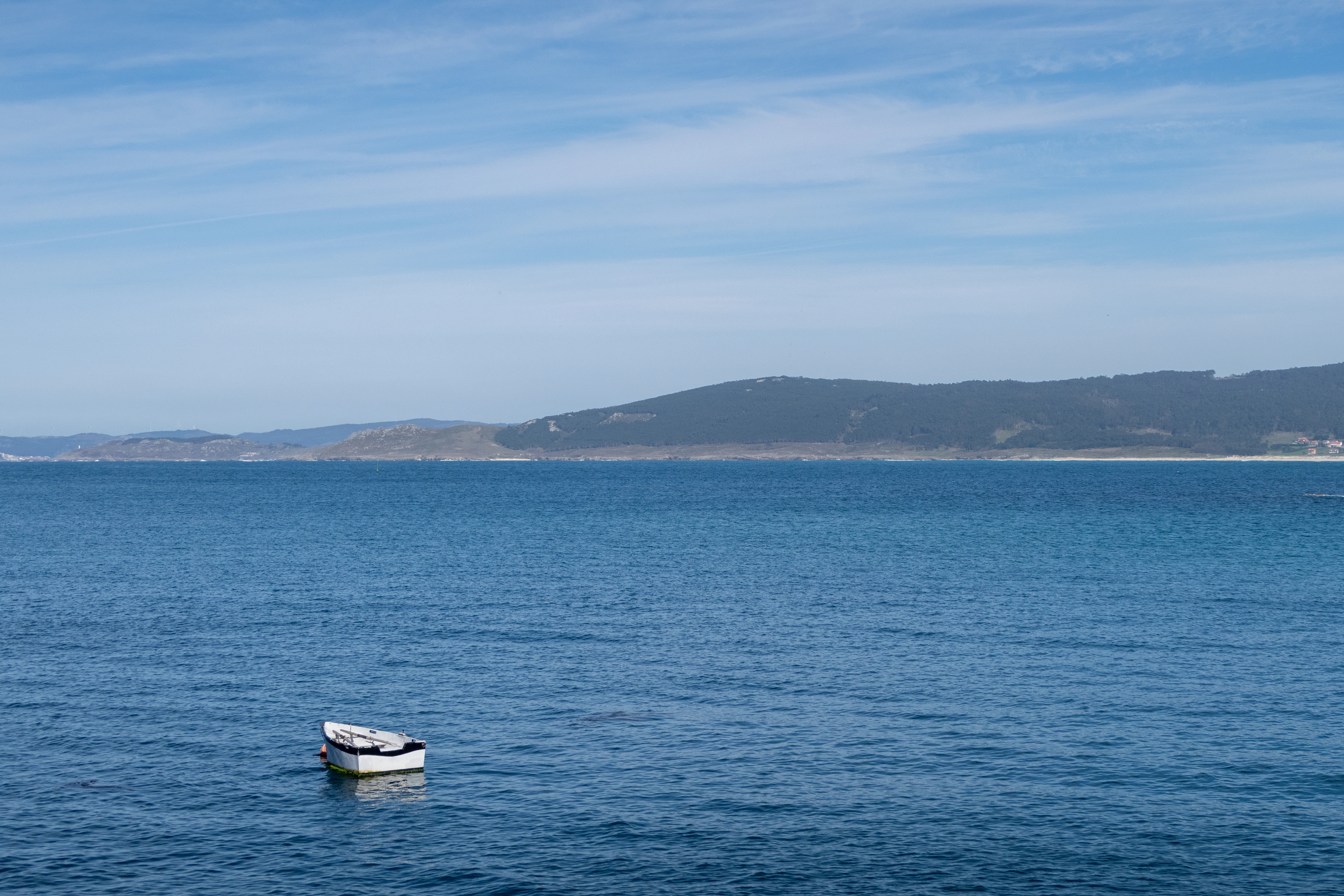 Small boat floats on calm blue ocean water.