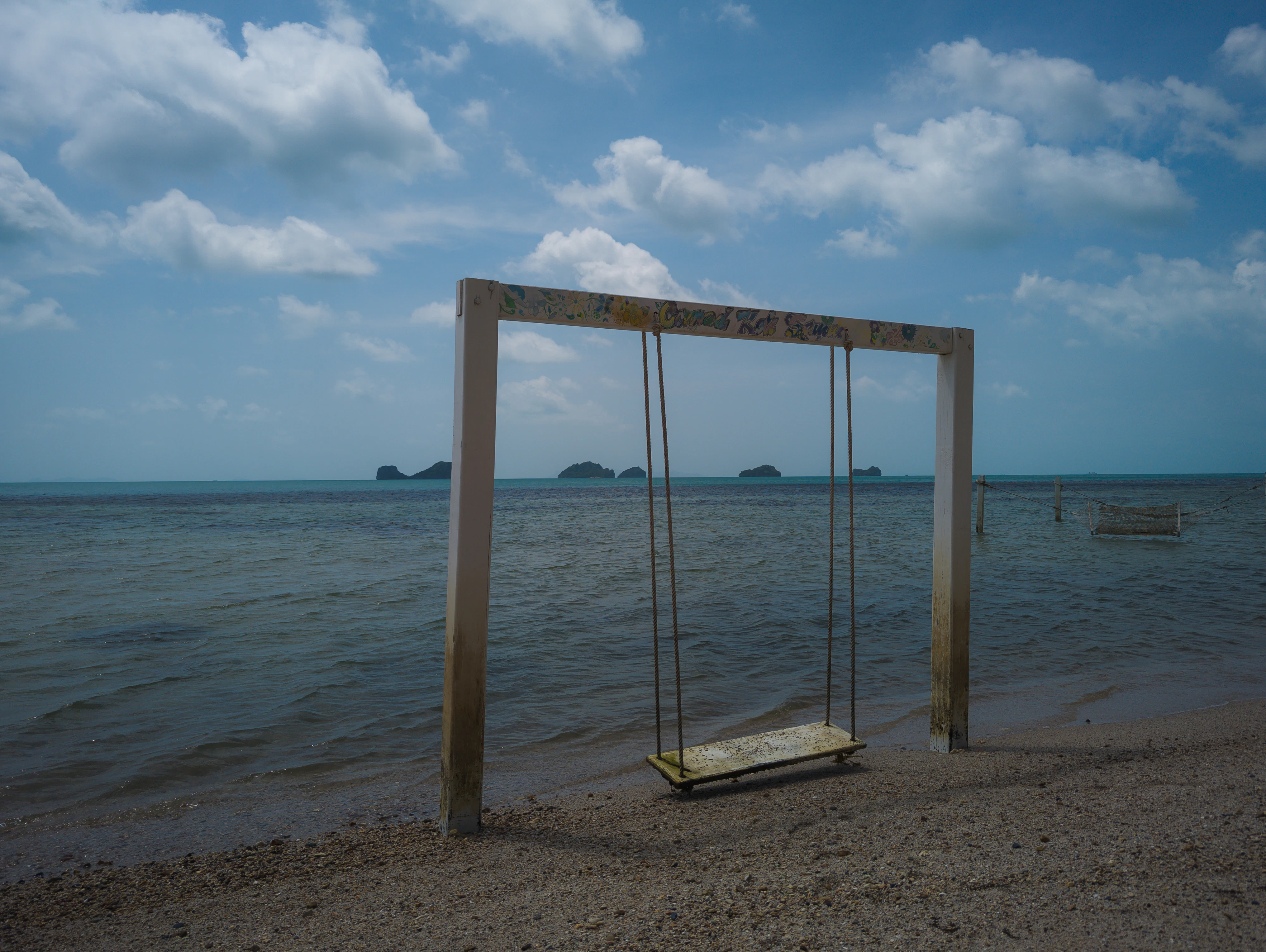 a wooden swing sitting on top of a sandy beach