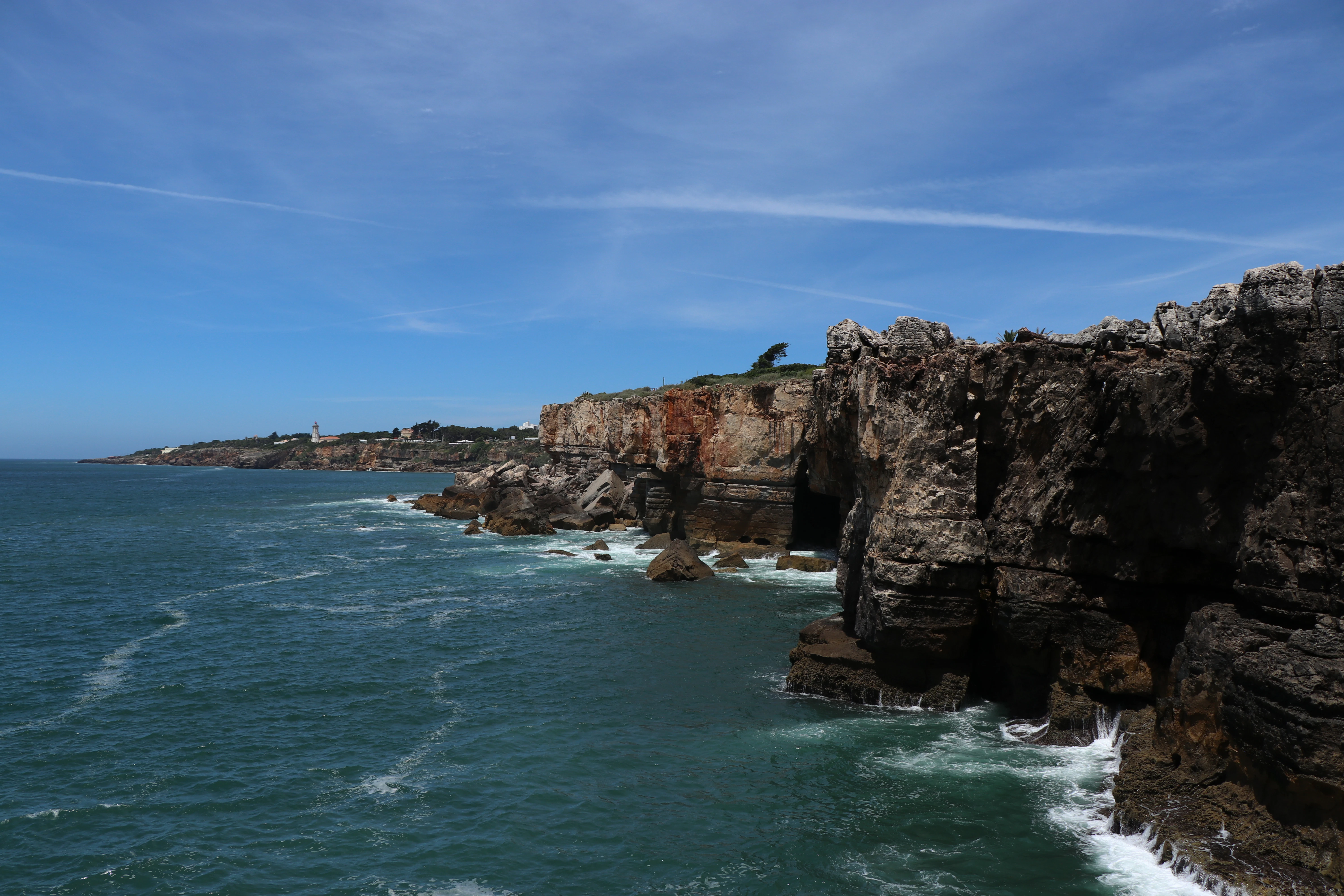 brown rock formation on sea under blue sky during daytime