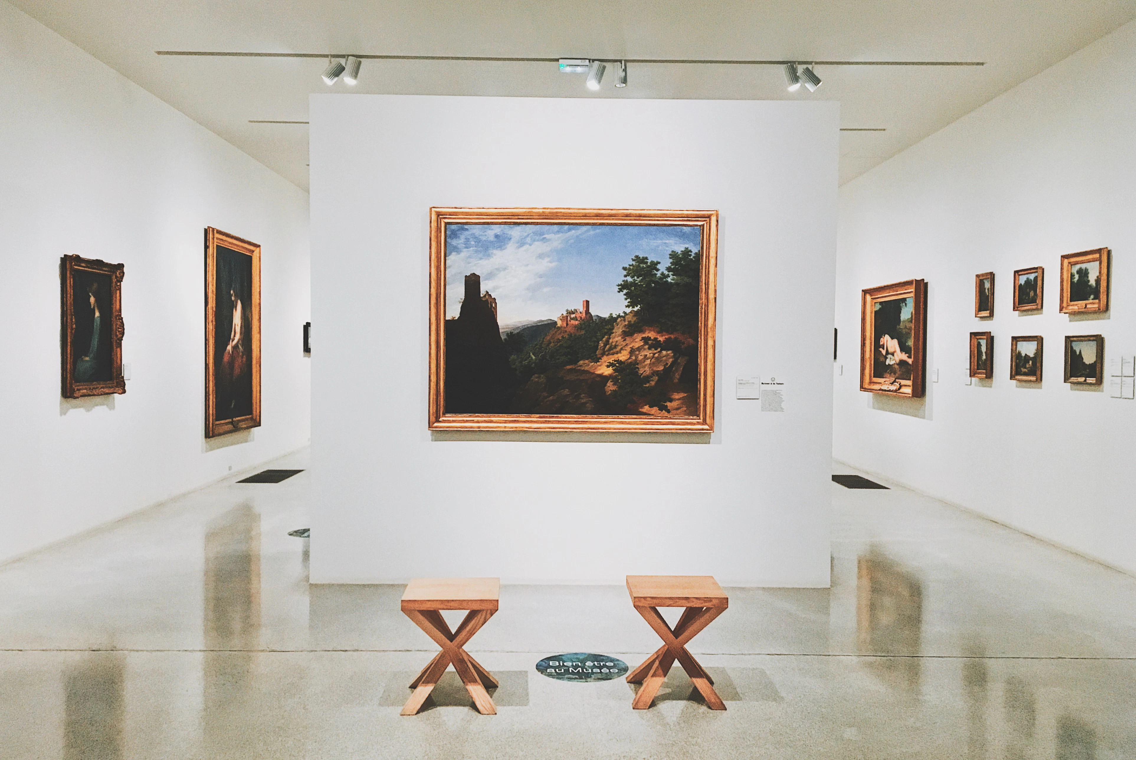 A room filled with lots of paintings and benches