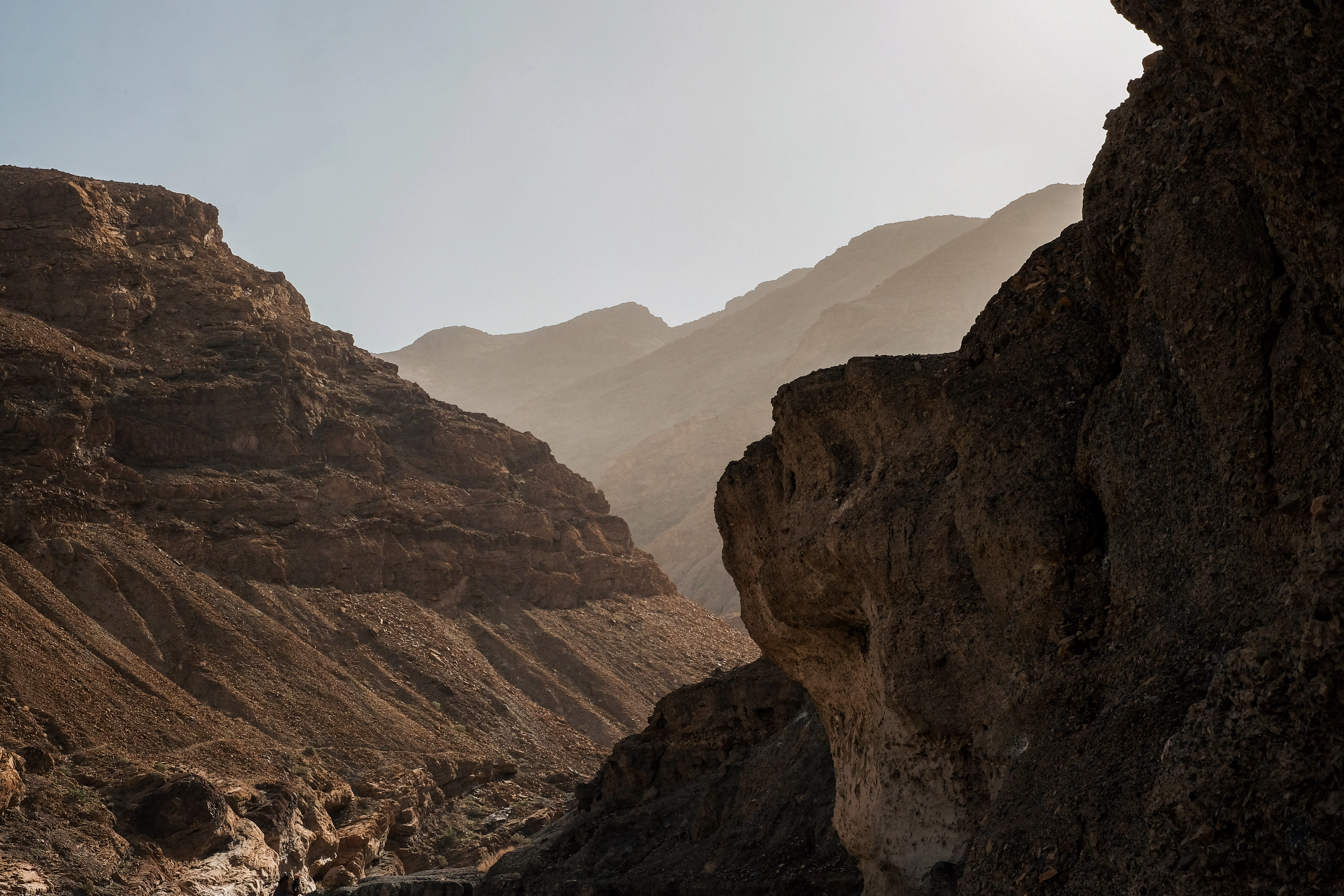 Sunlight illuminates a rocky canyon with layered mountains.