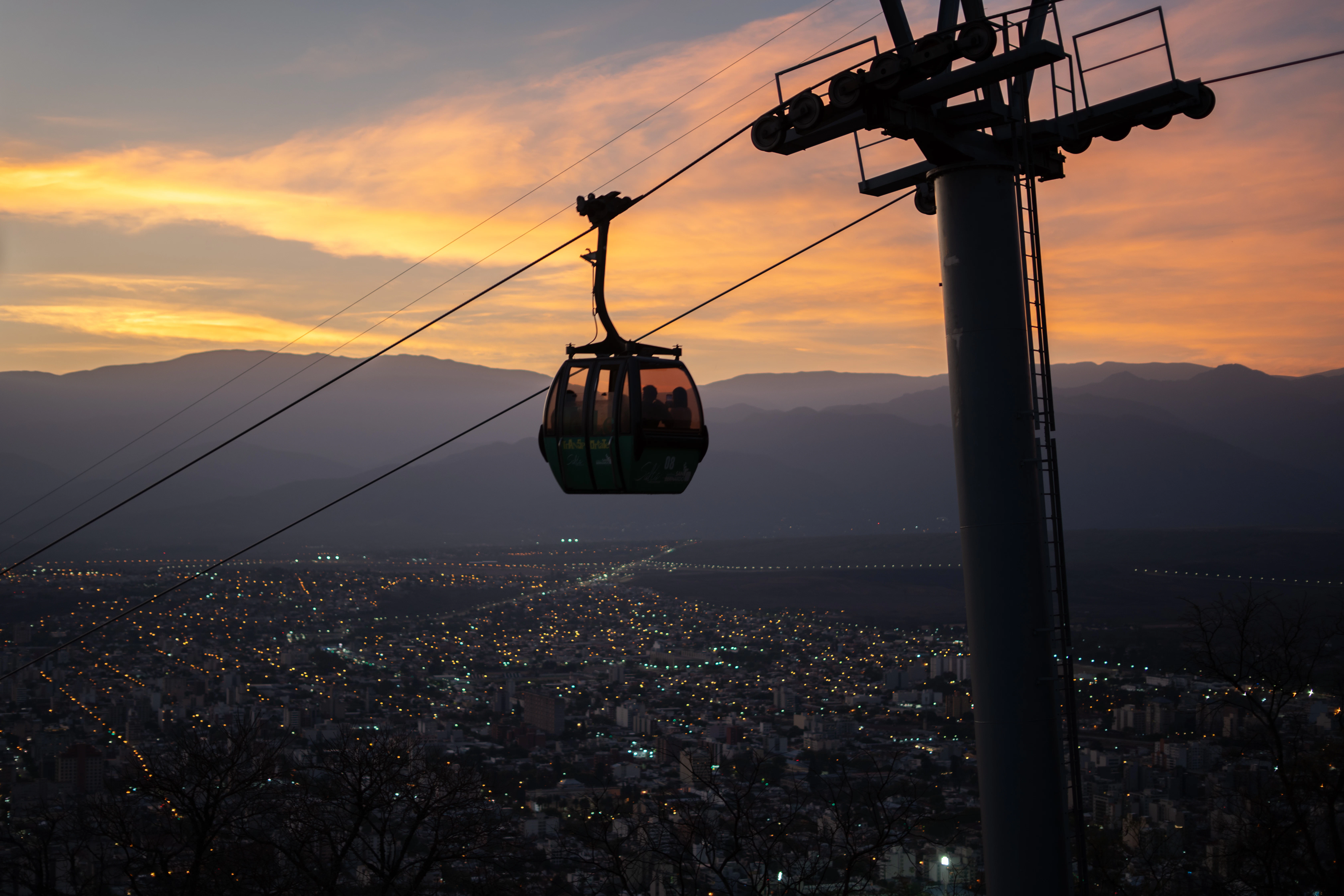 Cable car ascending over city at sunset