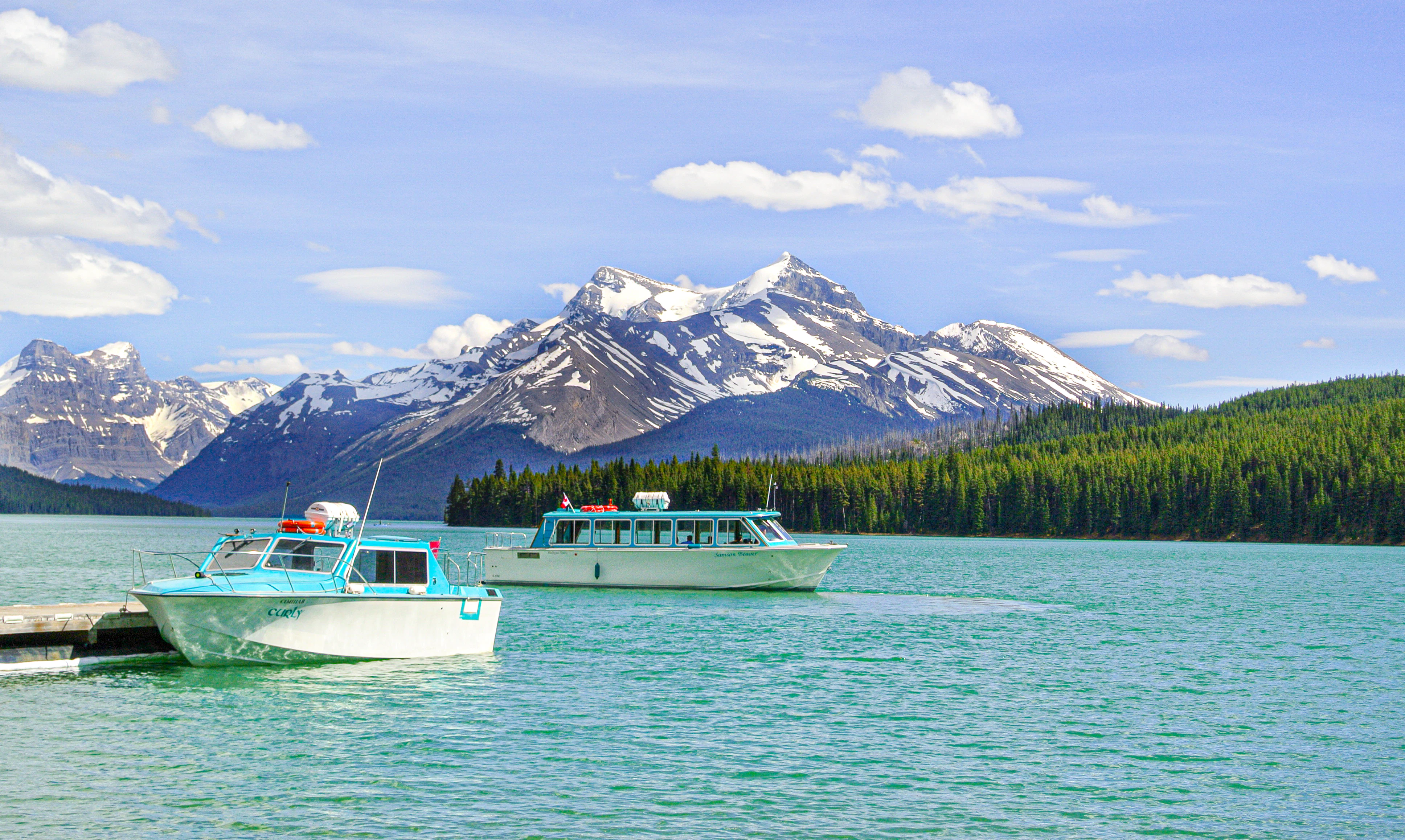 white boat on body of water near mountain during daytime