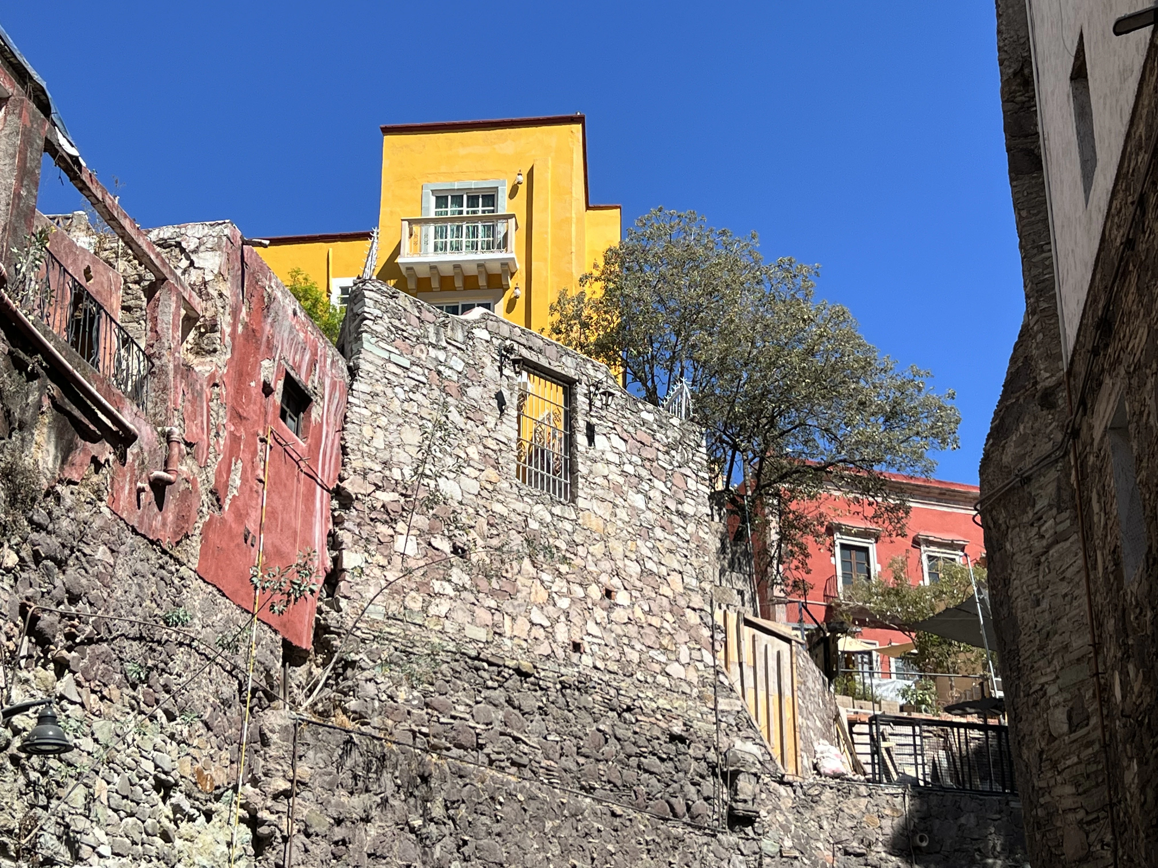 a yellow building is on top of a stone wall