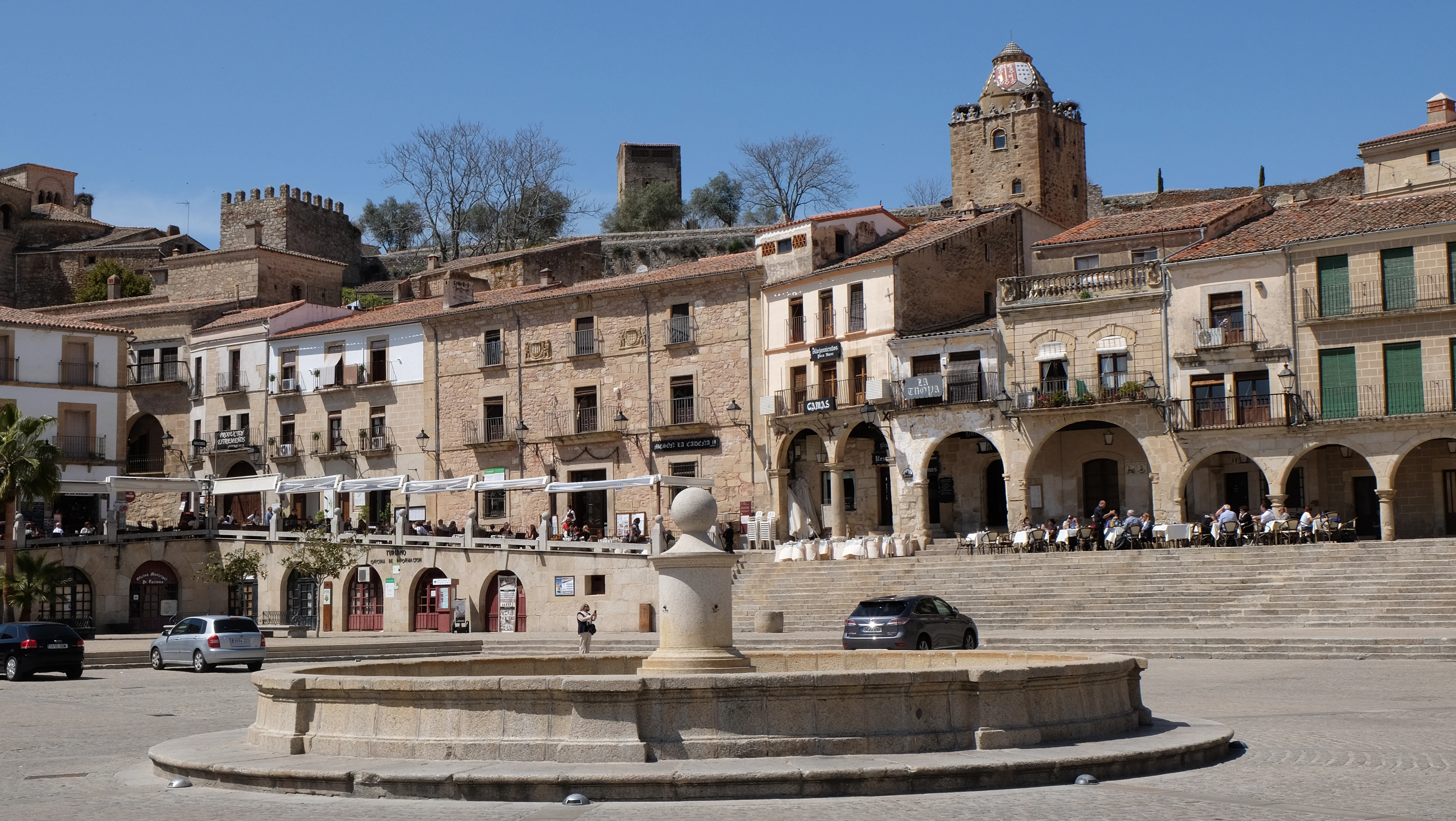 Old buildings surround a fountain in a sunny plaza.
