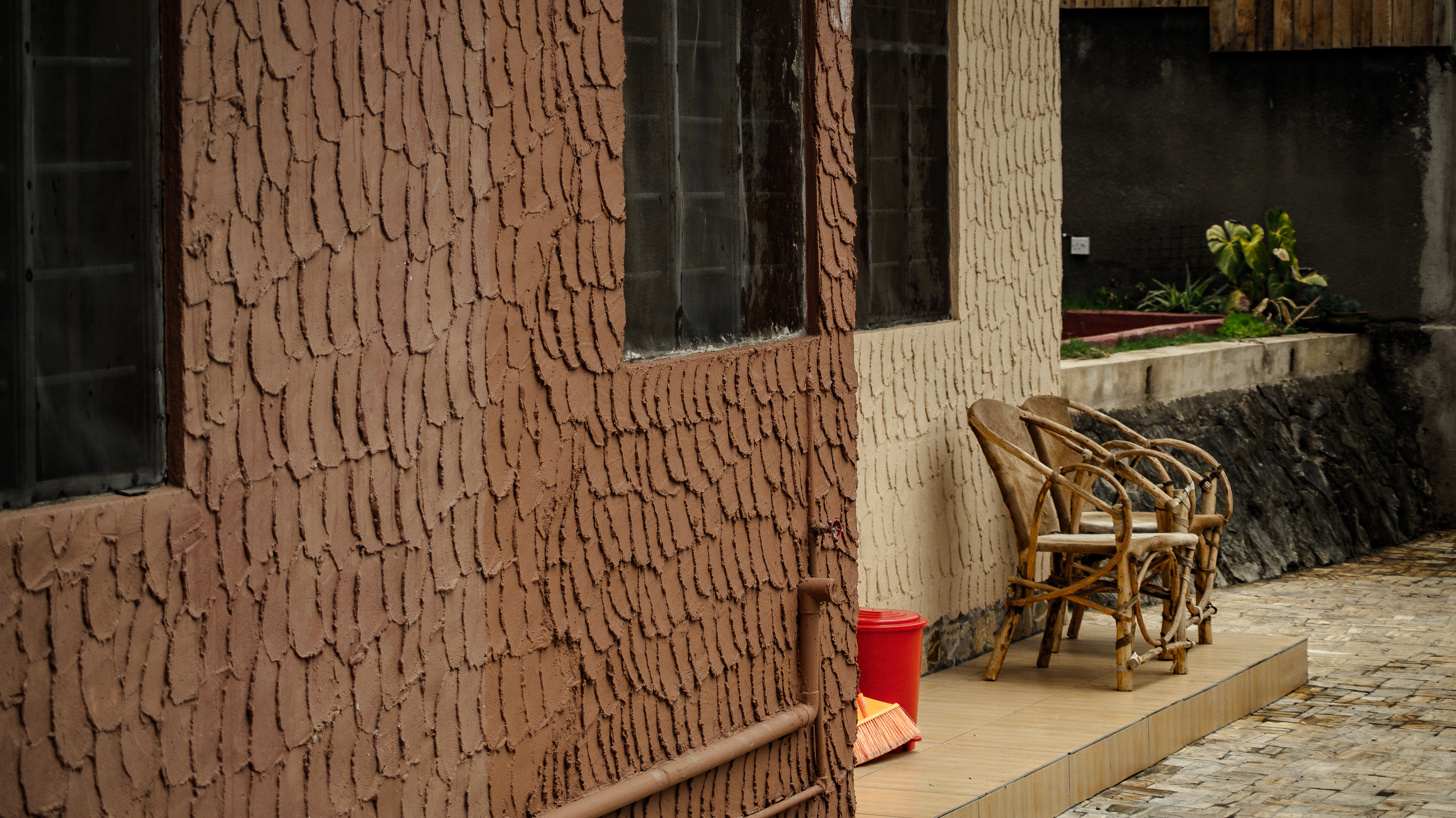 brown wooden armchair beside red plastic trash bin