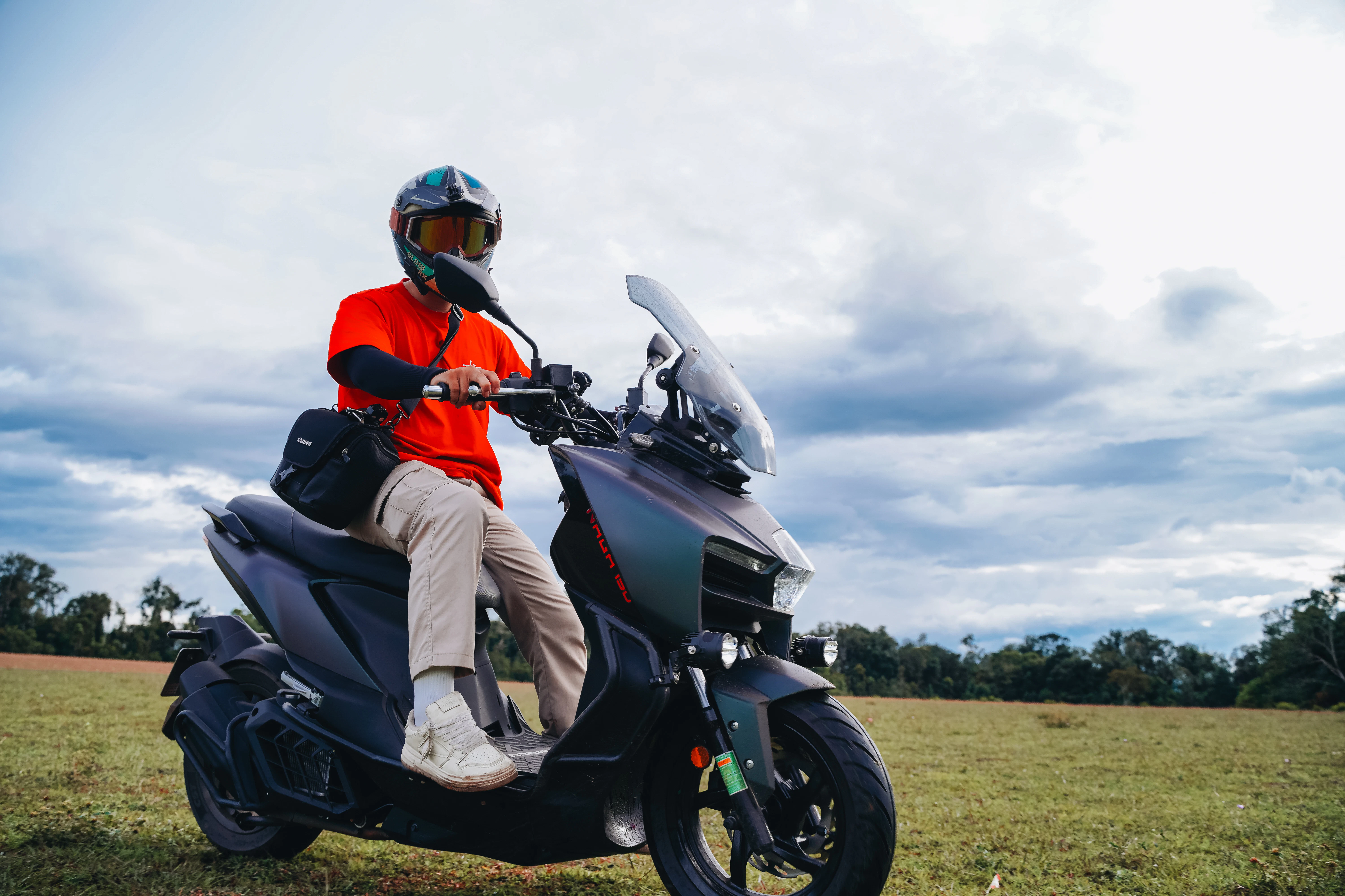 Person in helmet riding a dark scooter outdoors.