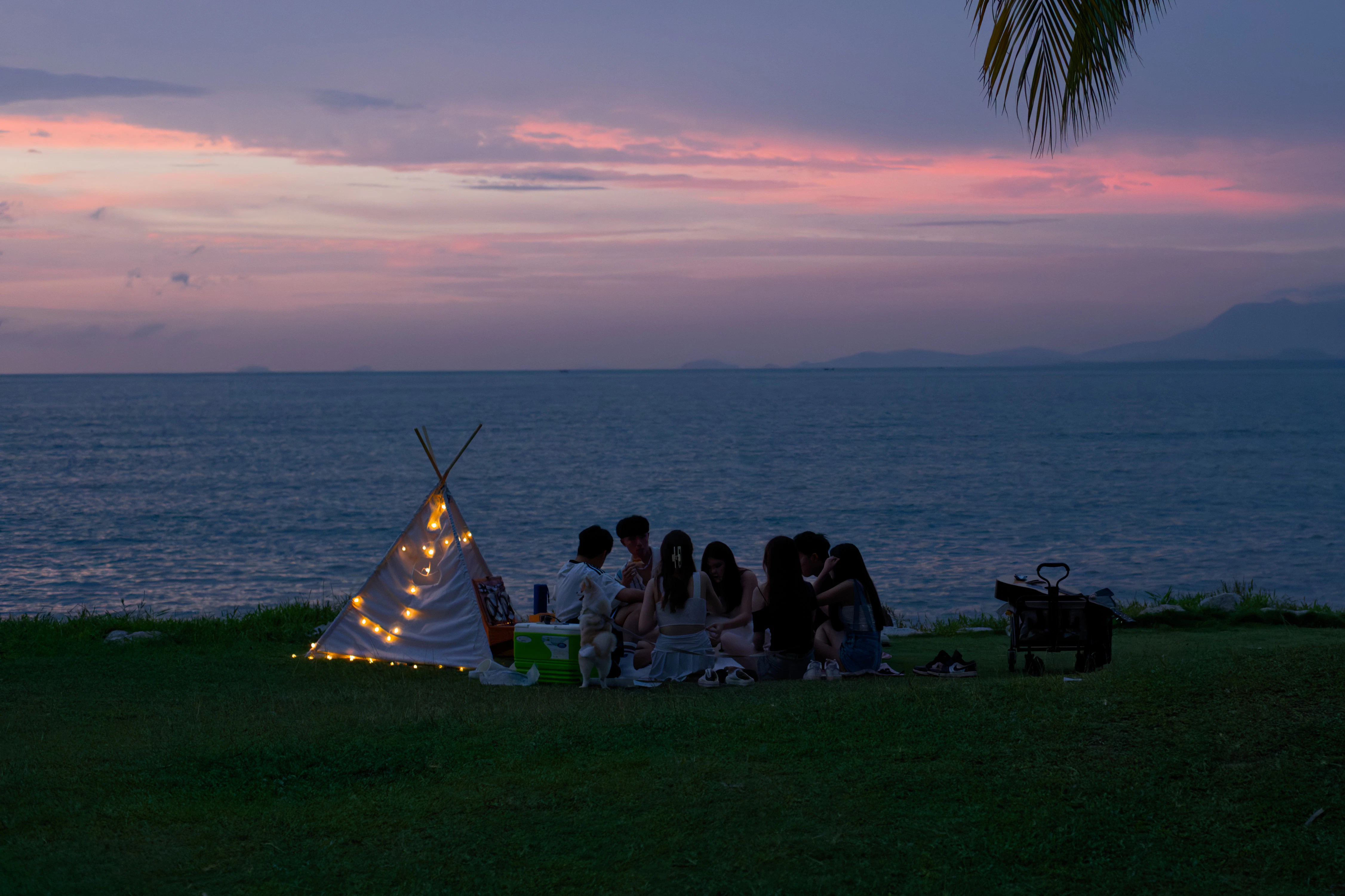 Friends enjoy a sunset picnic by the sea.