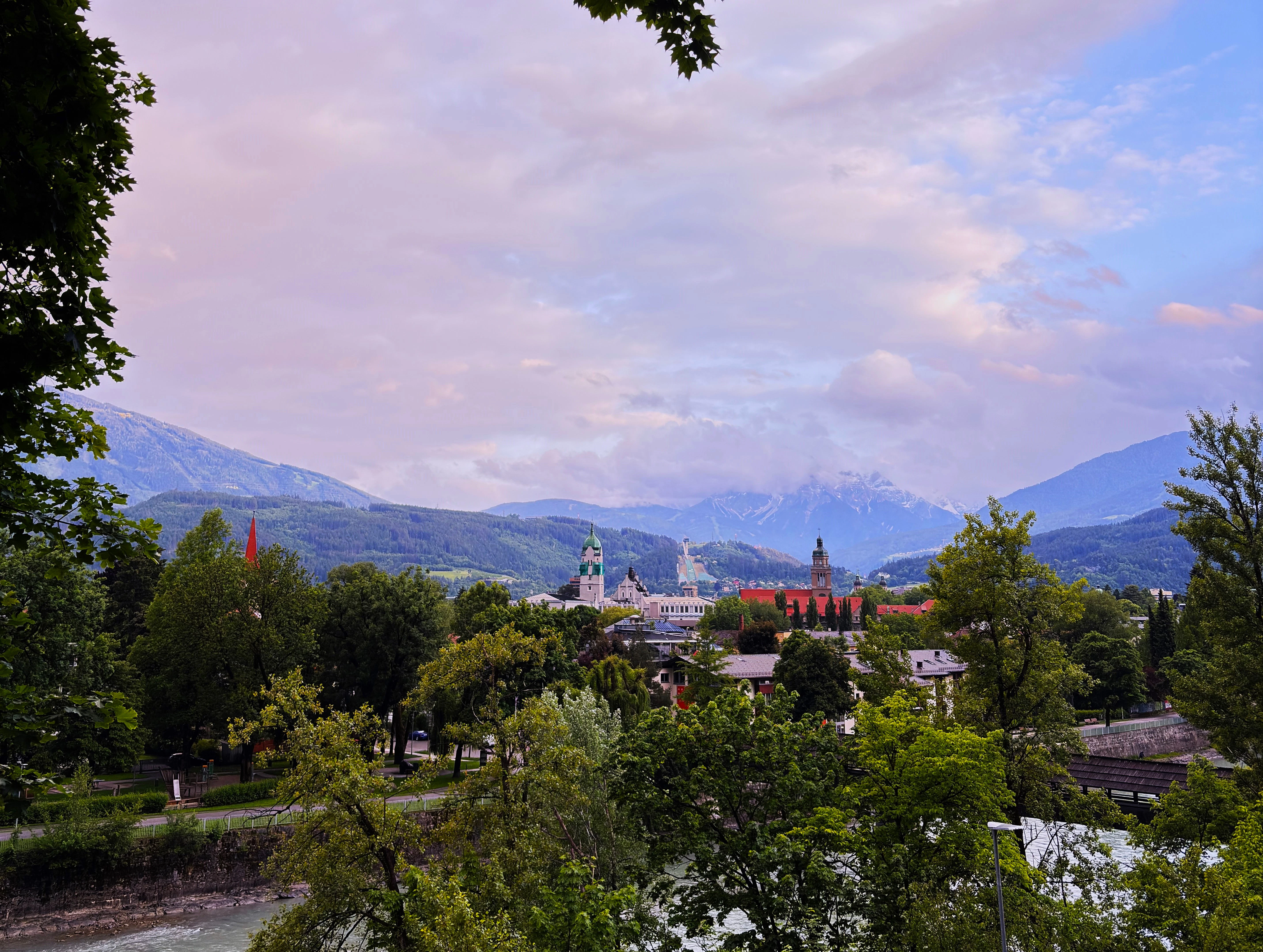 Town nestled between green trees and snowy mountains.