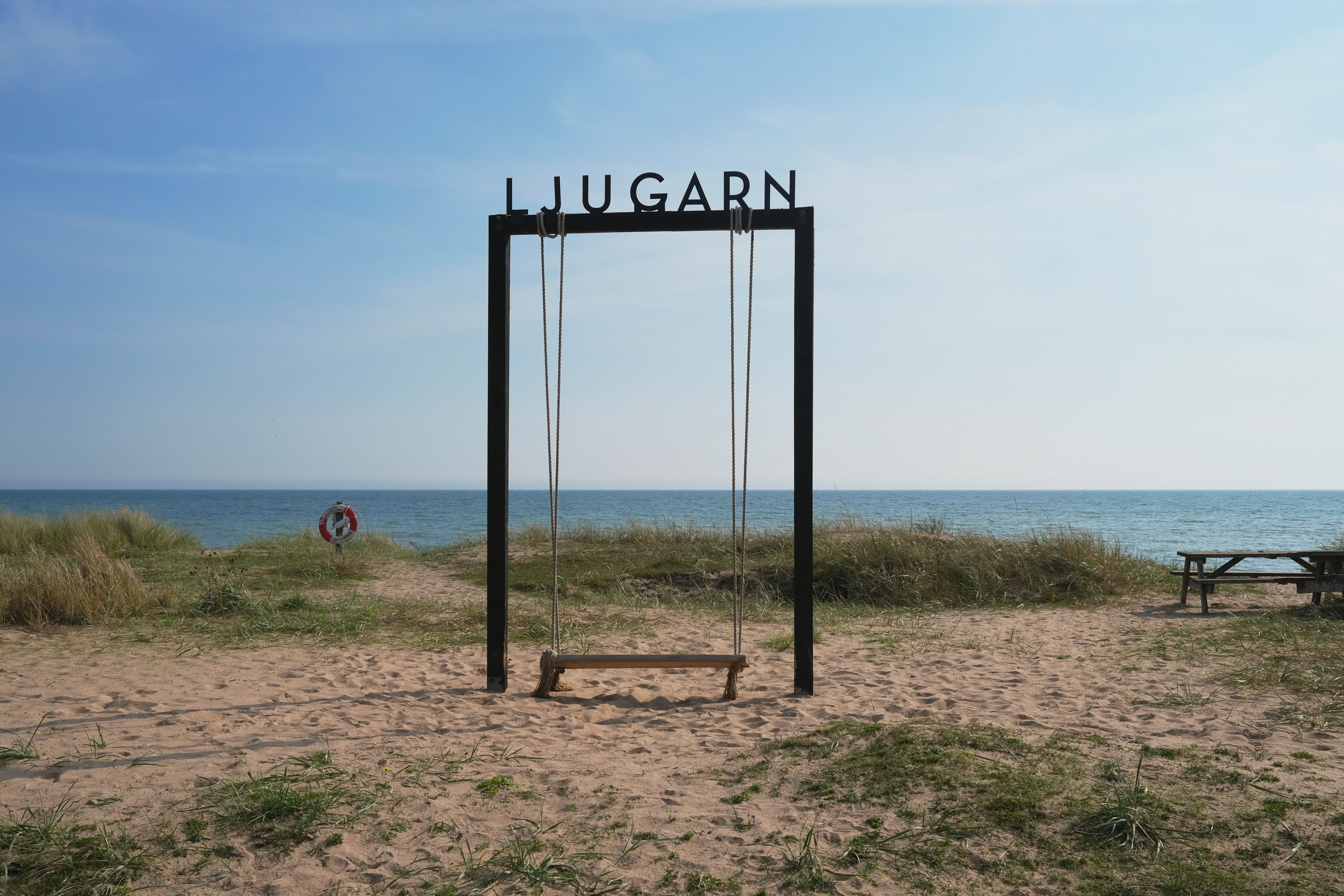 Swing set on a sandy beach with ocean background