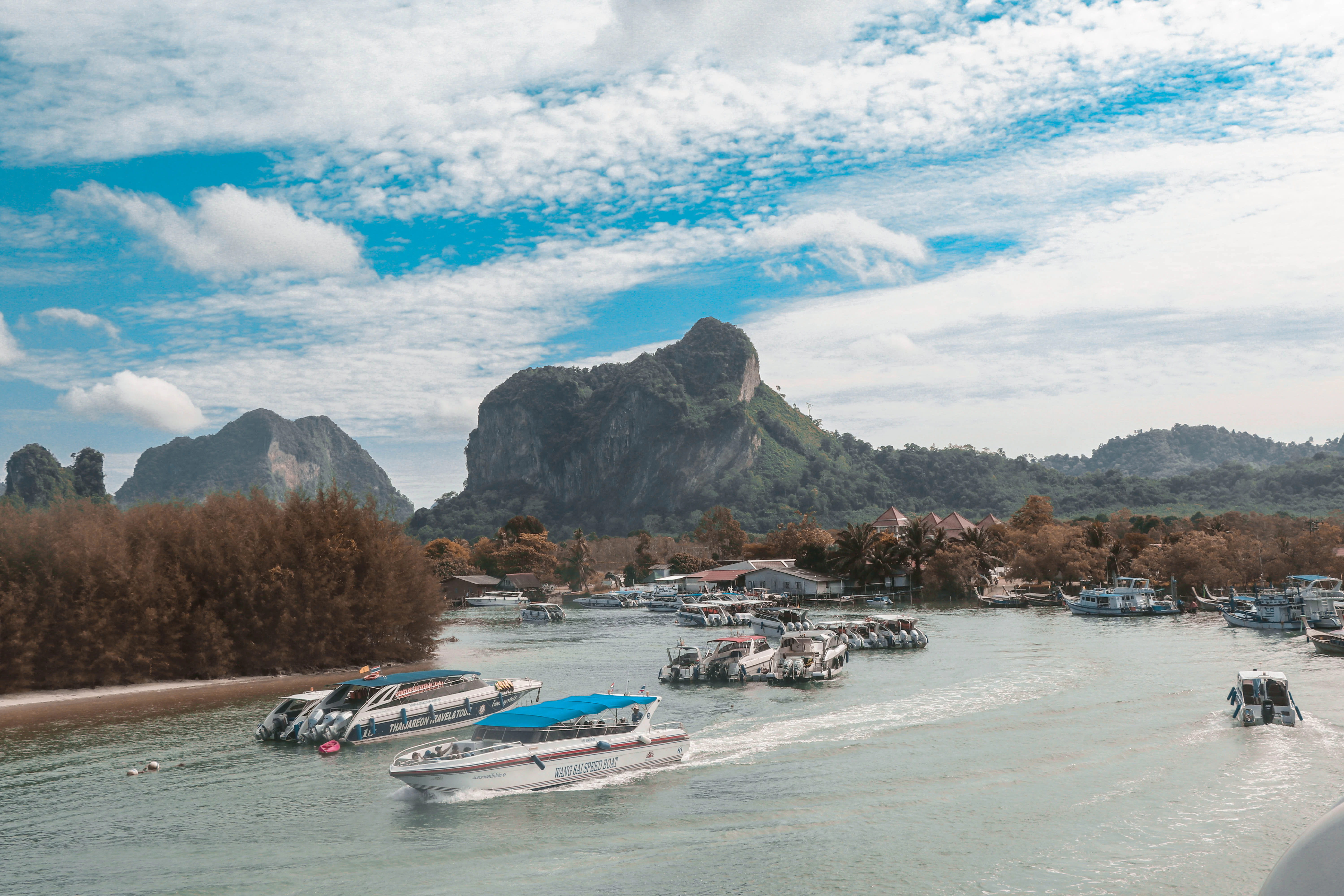 a body of water with boats and a rocky mountain in the background