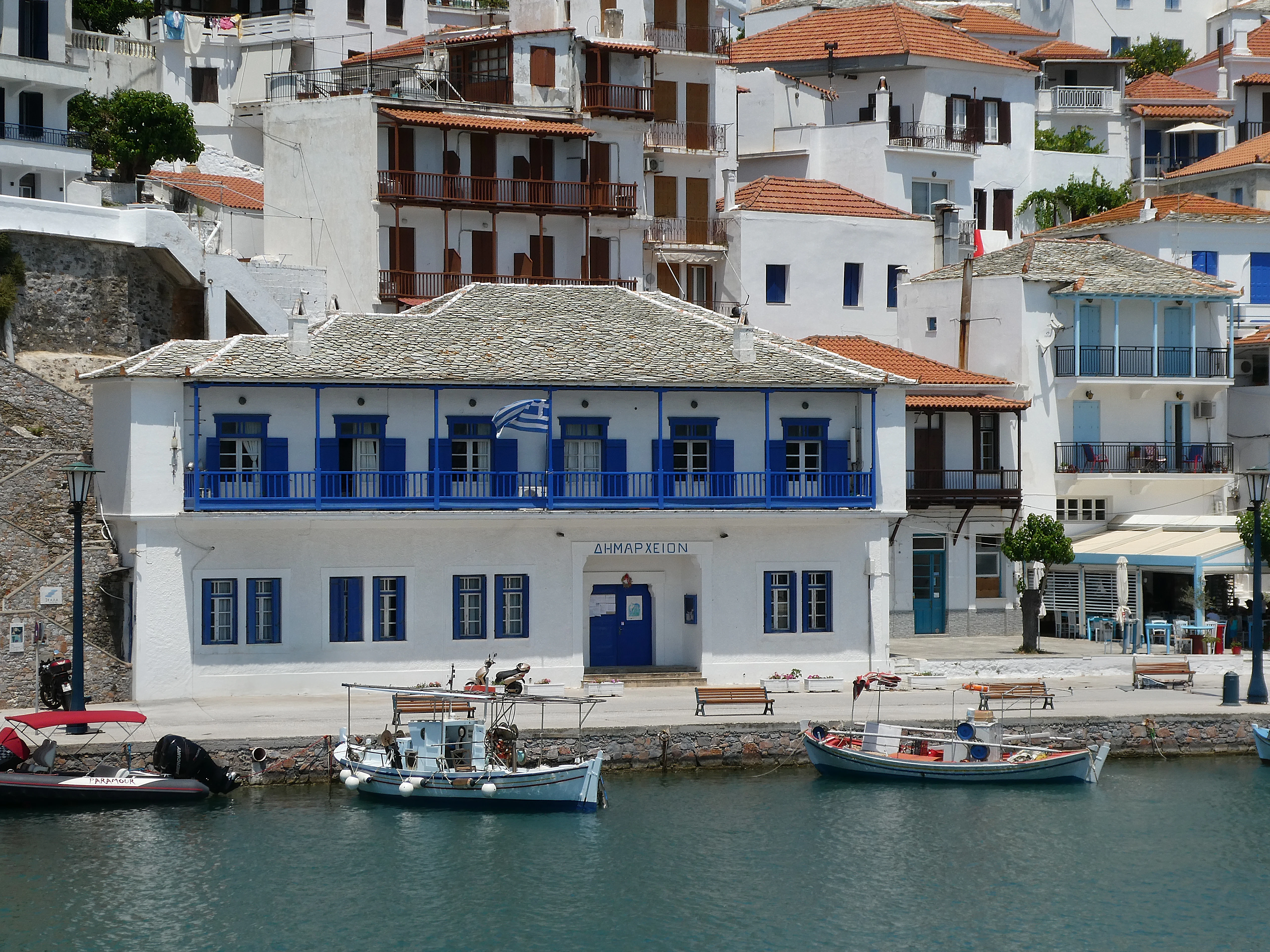 a white building with blue shutters next to a body of water