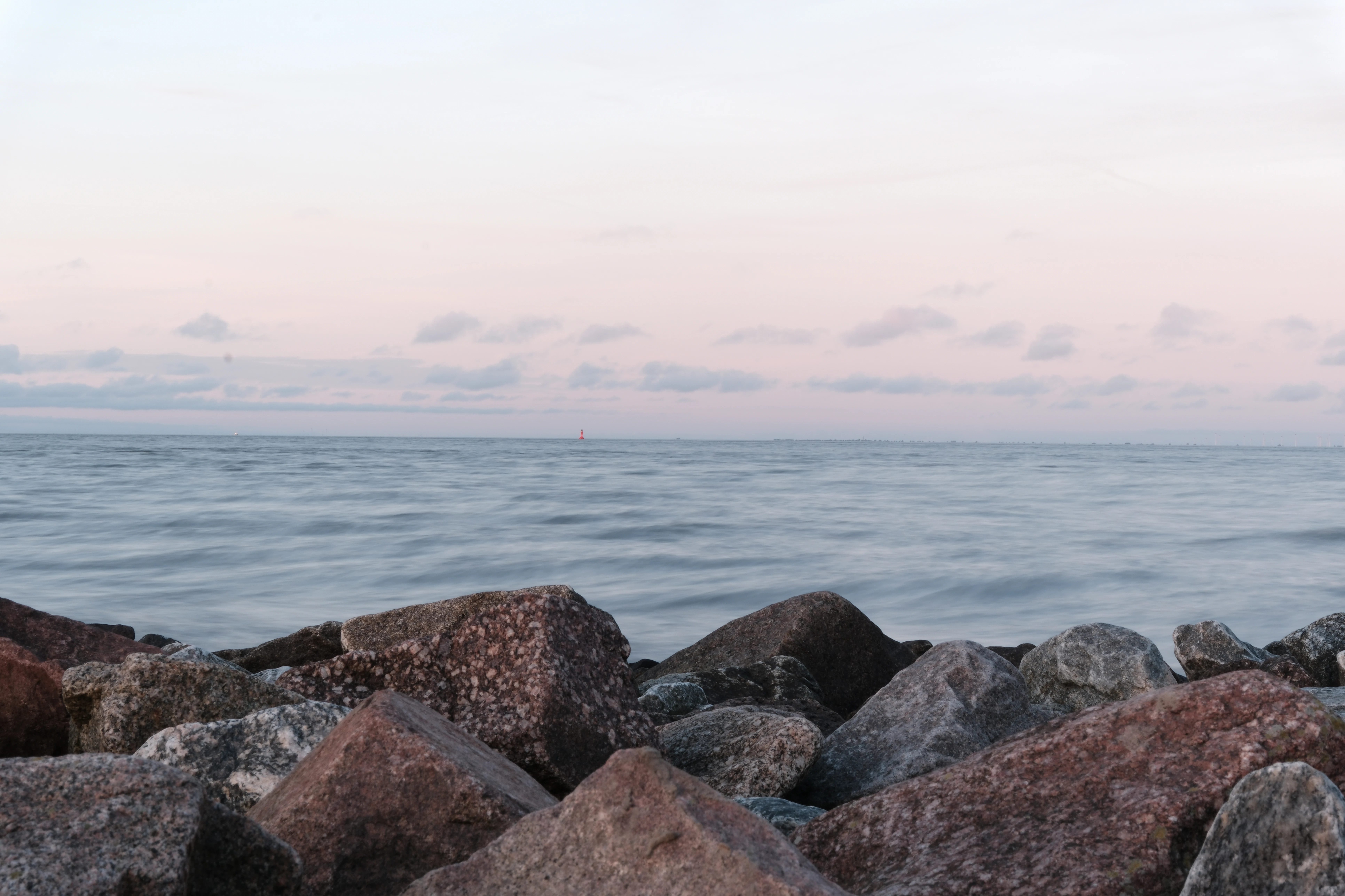 Rocky shore with a calm ocean and pastel sky