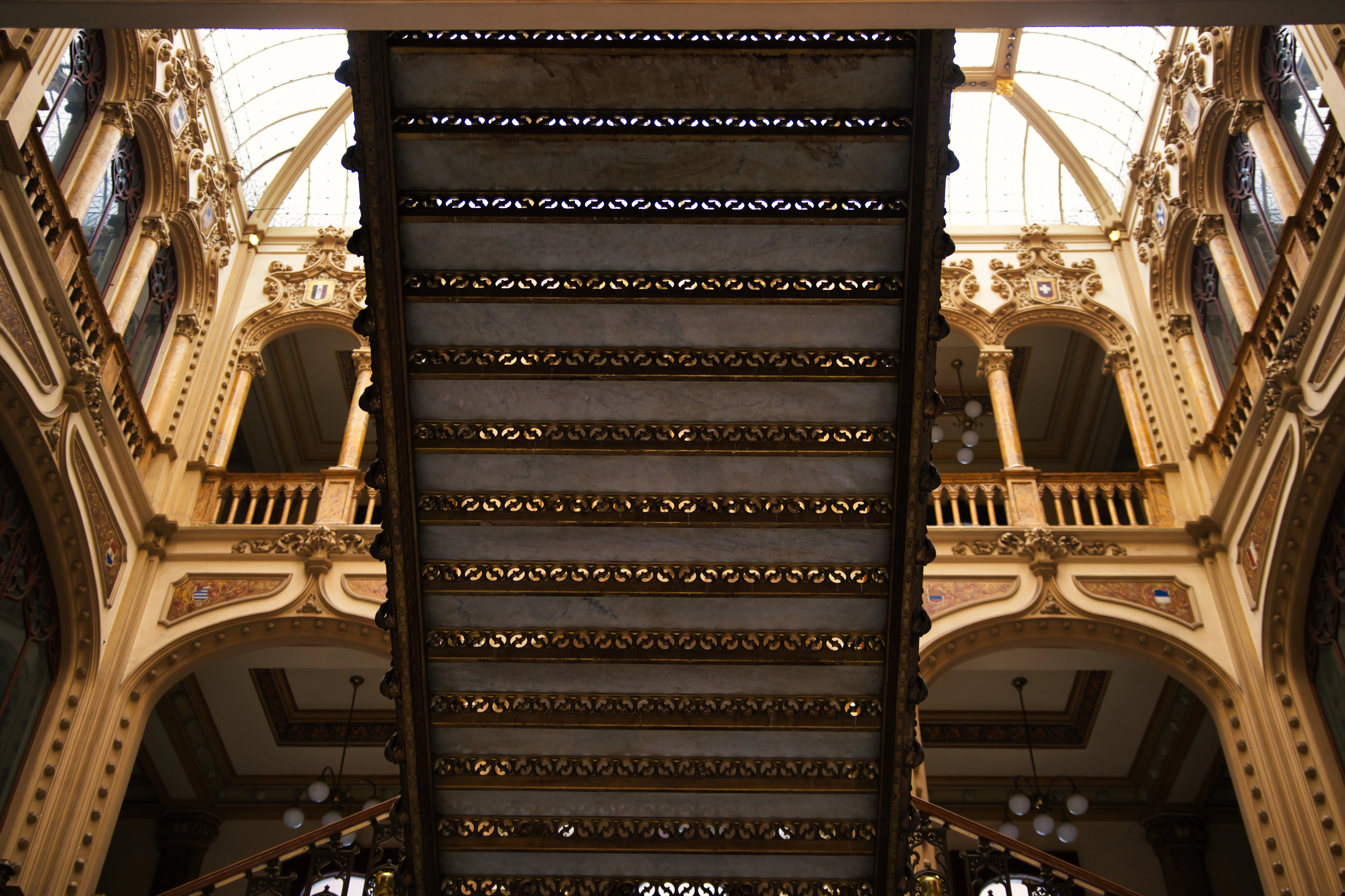 Ornate staircase inside a grand building with skylights.