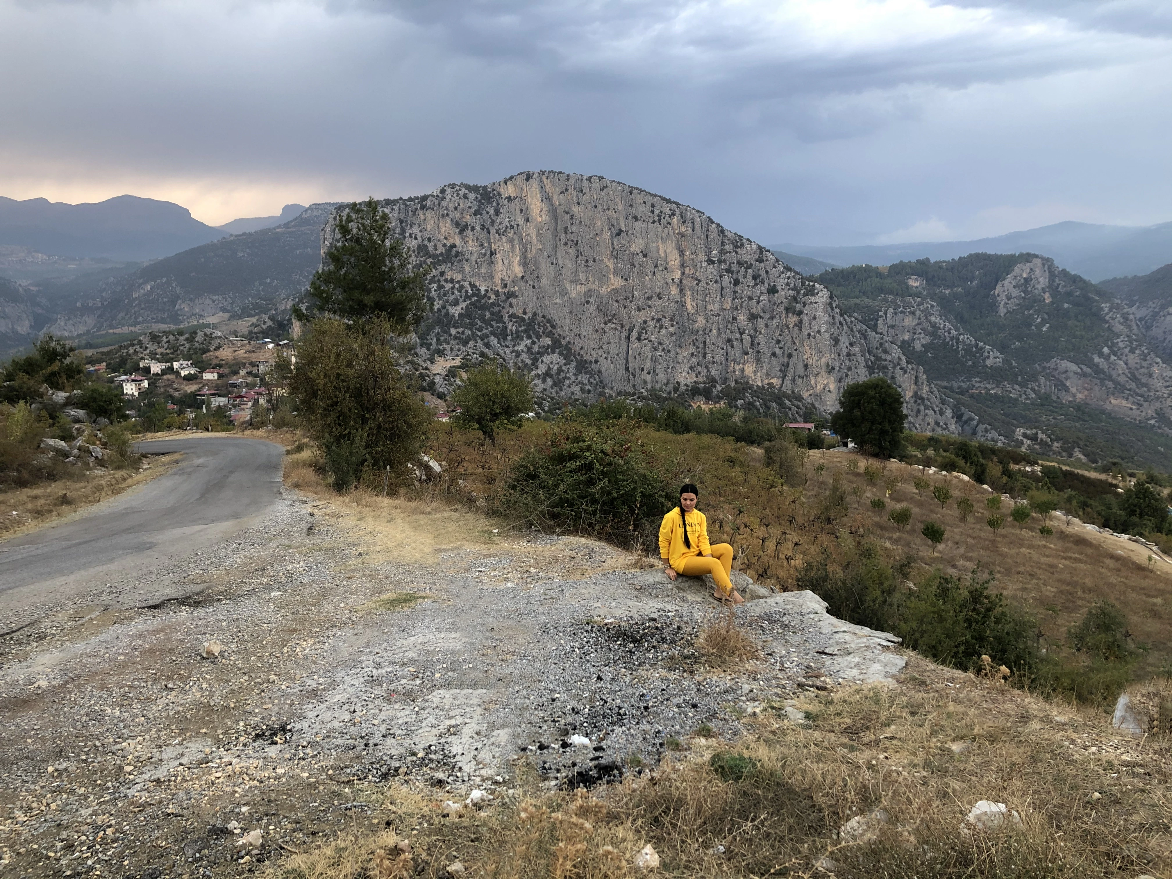 person in yellow jacket sitting on brown rock formation during daytime