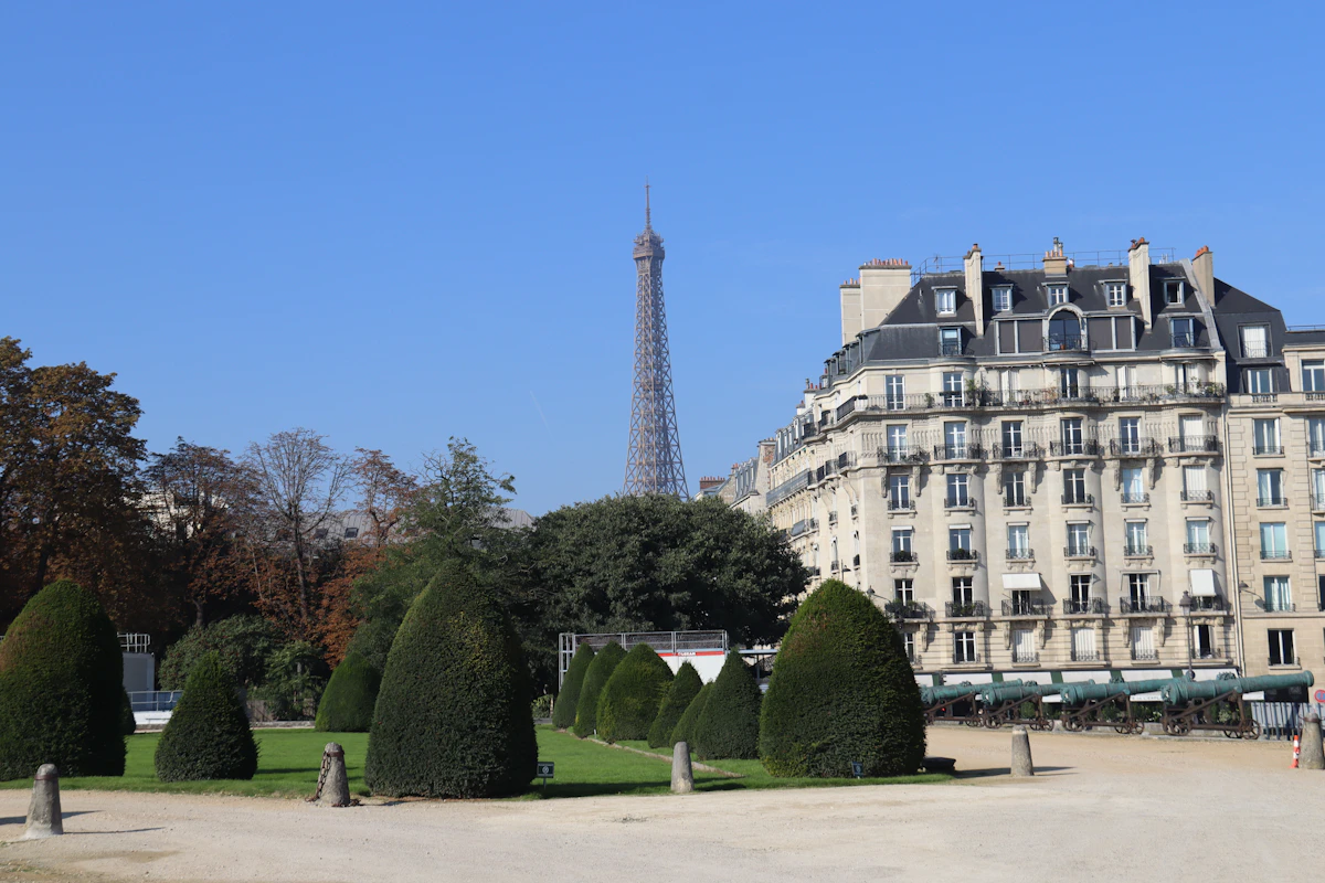 Eiffel tower viewed from a garden with manicured bushes.