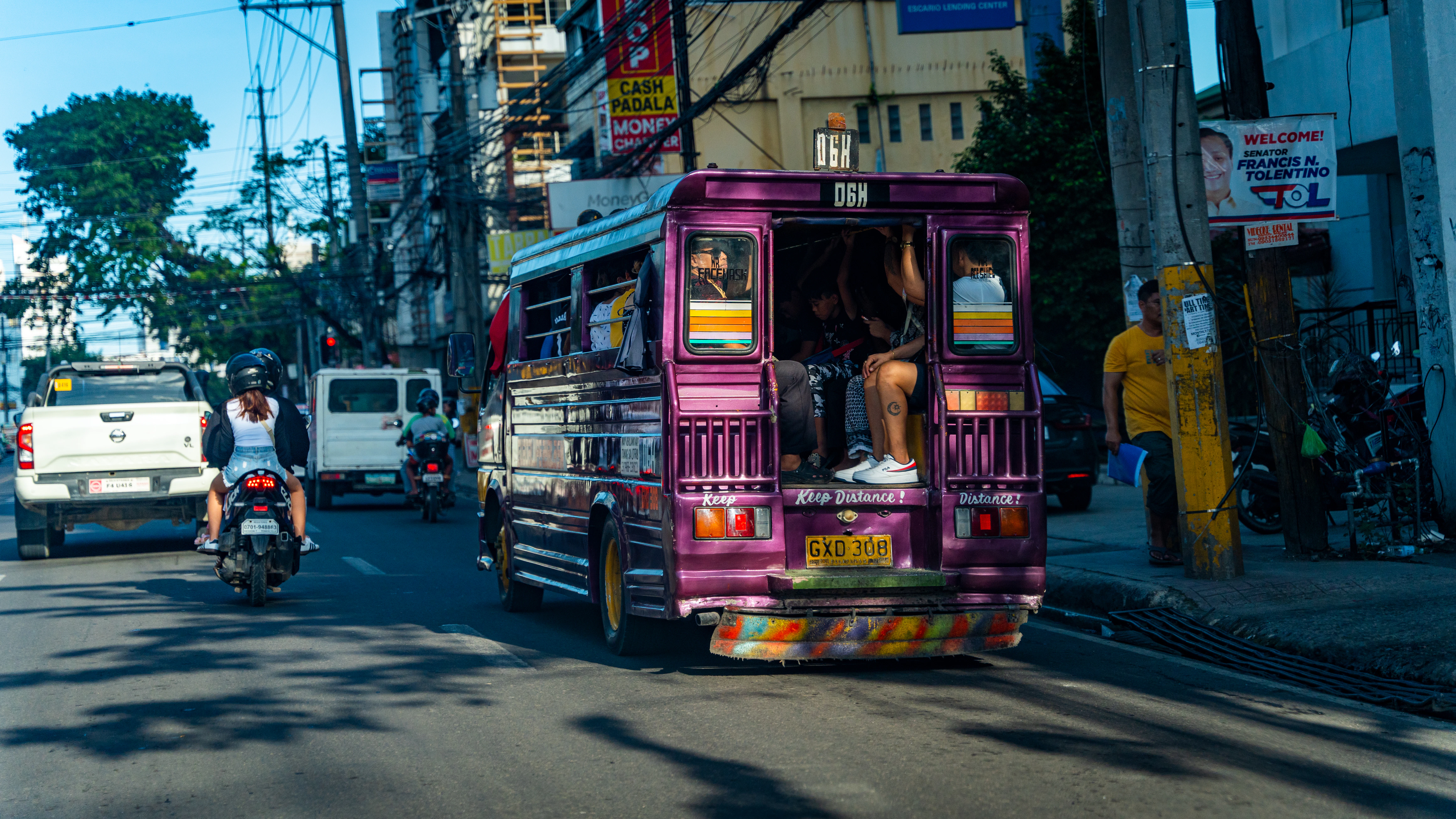a purple bus driving down a street next to traffic